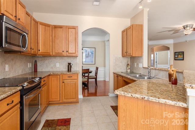 kitchen with stainless steel appliances, ornamental molding, ceiling fan, light stone counters, and tasteful backsplash