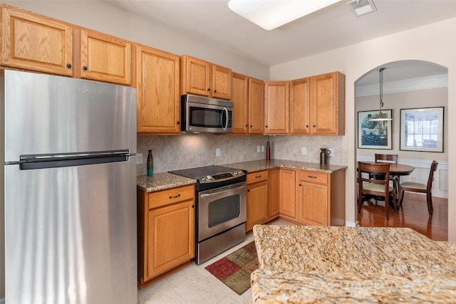 kitchen with crown molding, stainless steel appliances, light stone counters, decorative backsplash, and light tile patterned floors