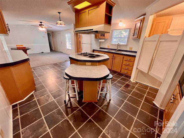 kitchen with ventilation hood, a center island, a textured ceiling, white appliances, and ceiling fan