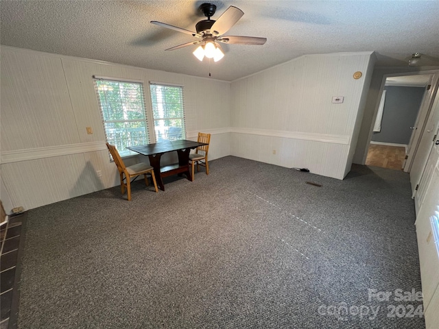 carpeted dining room featuring a textured ceiling, wooden walls, and ceiling fan