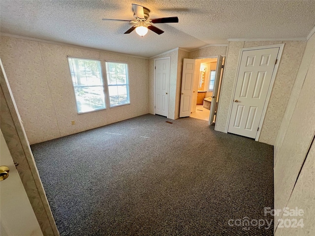 unfurnished bedroom with dark carpet, lofted ceiling, a textured ceiling, and ceiling fan