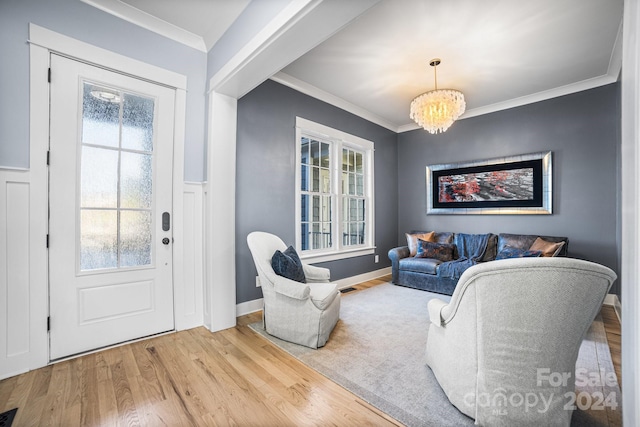 living room with wood-type flooring, ornamental molding, and a chandelier