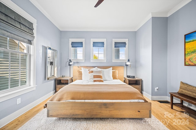 bedroom featuring light hardwood / wood-style flooring, multiple windows, crown molding, and ceiling fan