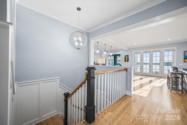 hall with light hardwood / wood-style floors, french doors, and ornamental molding