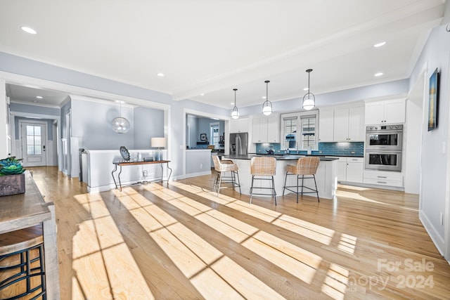 kitchen with a breakfast bar, stainless steel appliances, light hardwood / wood-style flooring, and white cabinets