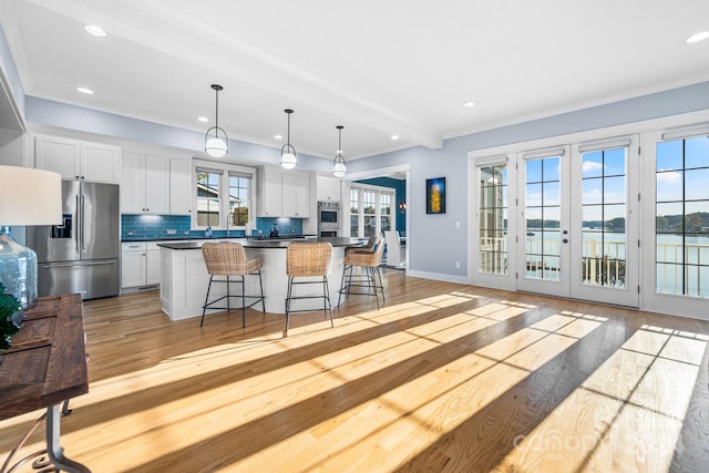 kitchen with french doors, white cabinetry, a water view, and stainless steel appliances