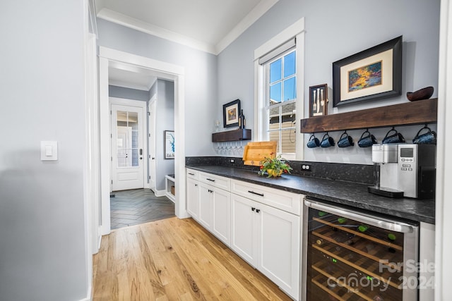 bar featuring wine cooler, ornamental molding, and white cabinets