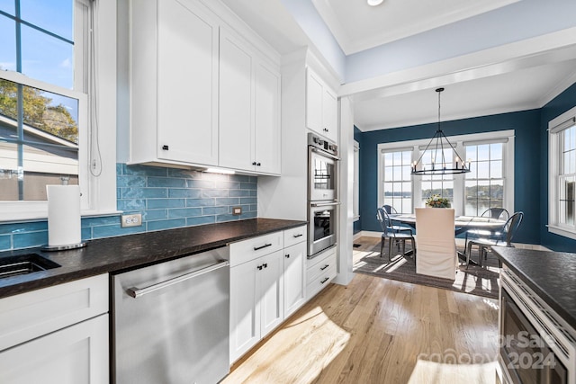 kitchen featuring white cabinets, hanging light fixtures, light hardwood / wood-style flooring, a notable chandelier, and stainless steel appliances