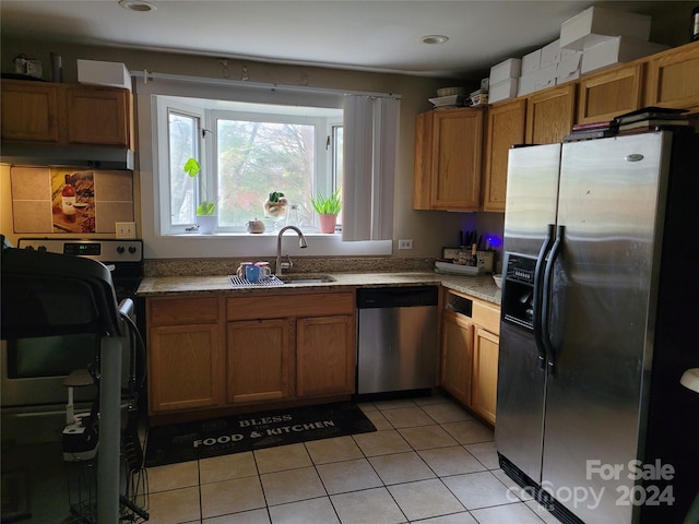 kitchen with light stone countertops, sink, light tile patterned floors, and stainless steel appliances