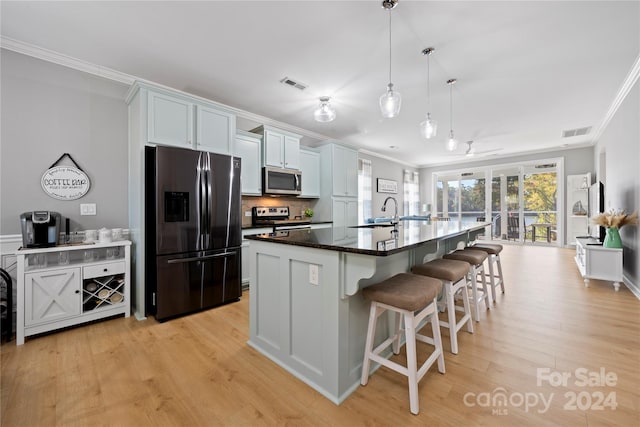 kitchen featuring appliances with stainless steel finishes, light hardwood / wood-style flooring, white cabinets, and an island with sink