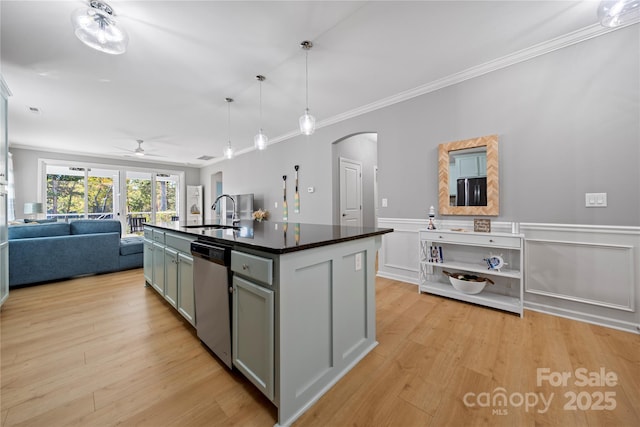 kitchen featuring arched walkways, open floor plan, light wood-type flooring, stainless steel dishwasher, and a sink