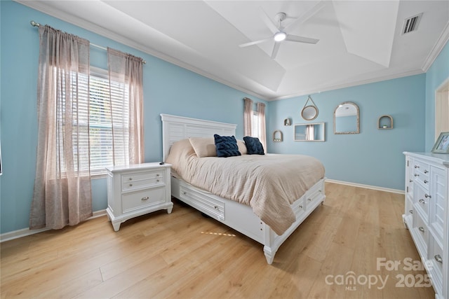 bedroom featuring a raised ceiling, visible vents, light wood-style floors, ornamental molding, and baseboards