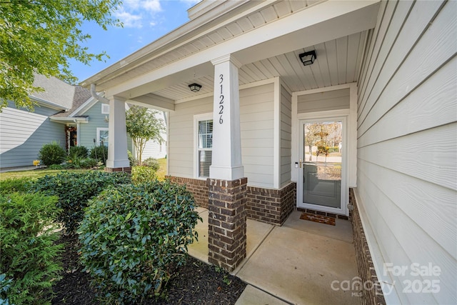 entrance to property with covered porch and brick siding