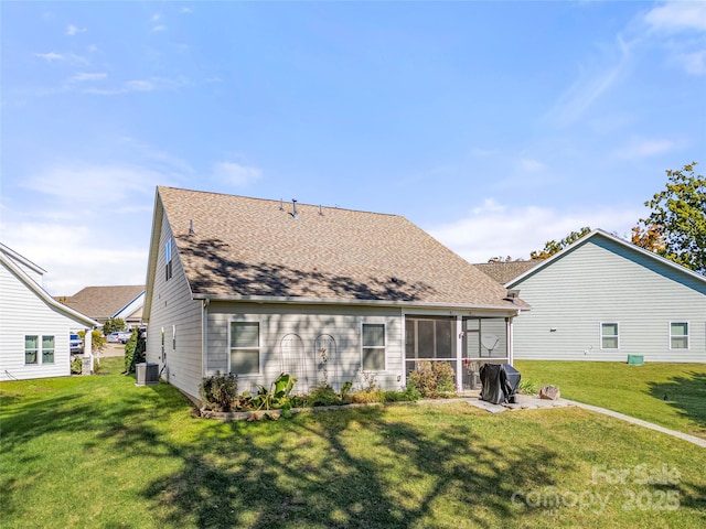 back of property with a sunroom, a shingled roof, central AC, and a lawn