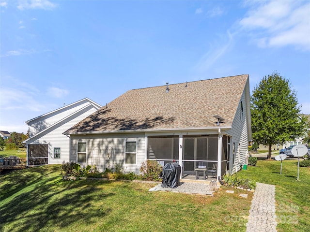 rear view of property with a shingled roof, a sunroom, a yard, and a patio