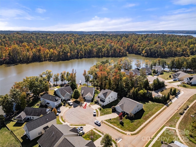 drone / aerial view with a residential view, a water view, and a wooded view