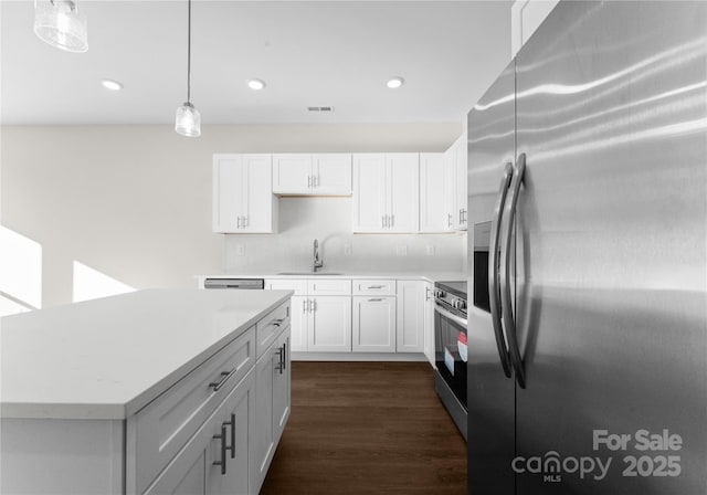 kitchen with a center island, sink, decorative light fixtures, white cabinetry, and stainless steel appliances