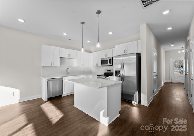 kitchen featuring sink, a center island, decorative light fixtures, white cabinets, and appliances with stainless steel finishes