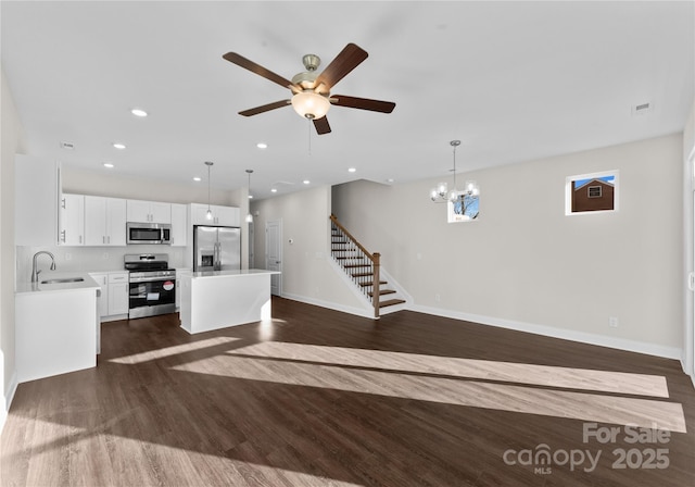 unfurnished living room with sink, ceiling fan with notable chandelier, and dark hardwood / wood-style floors