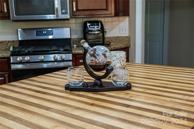 kitchen featuring appliances with stainless steel finishes, dark brown cabinetry, wood-type flooring, and backsplash