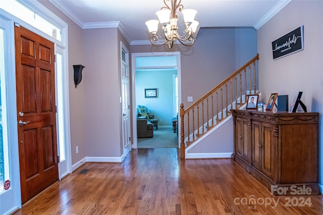 entryway with crown molding, wood-type flooring, and an inviting chandelier