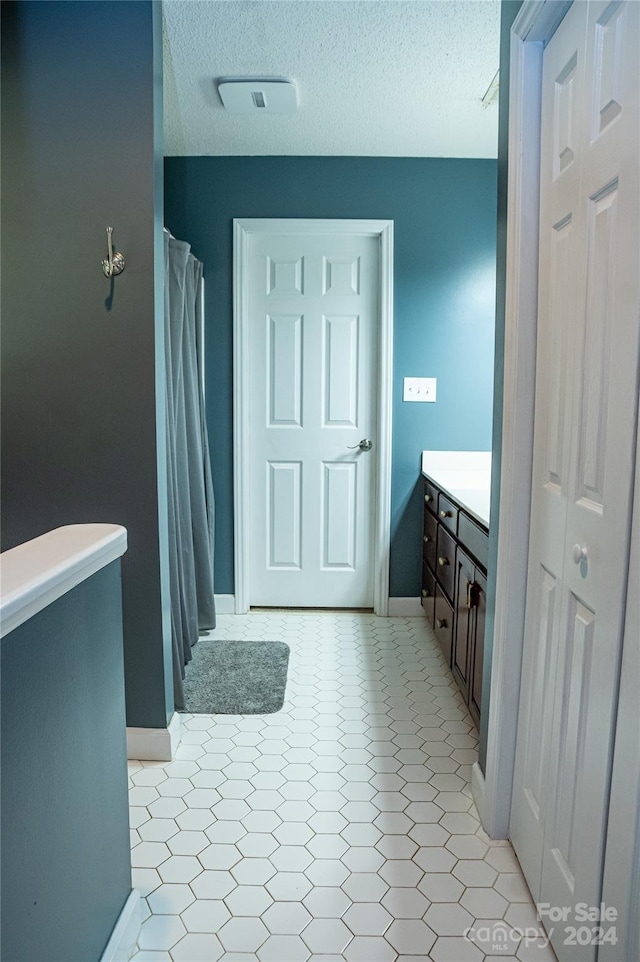 bathroom with vanity, a textured ceiling, and tile patterned floors