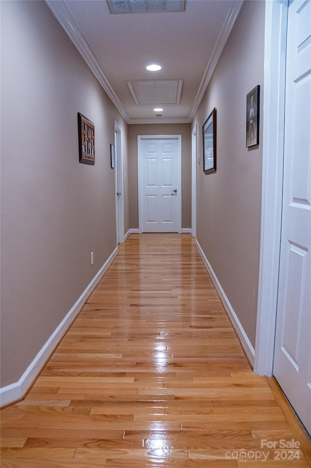 hallway with light hardwood / wood-style floors and ornamental molding