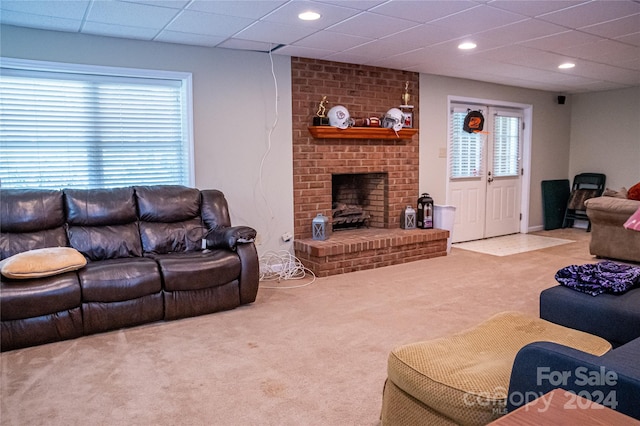 living room featuring a paneled ceiling, a fireplace, and carpet flooring