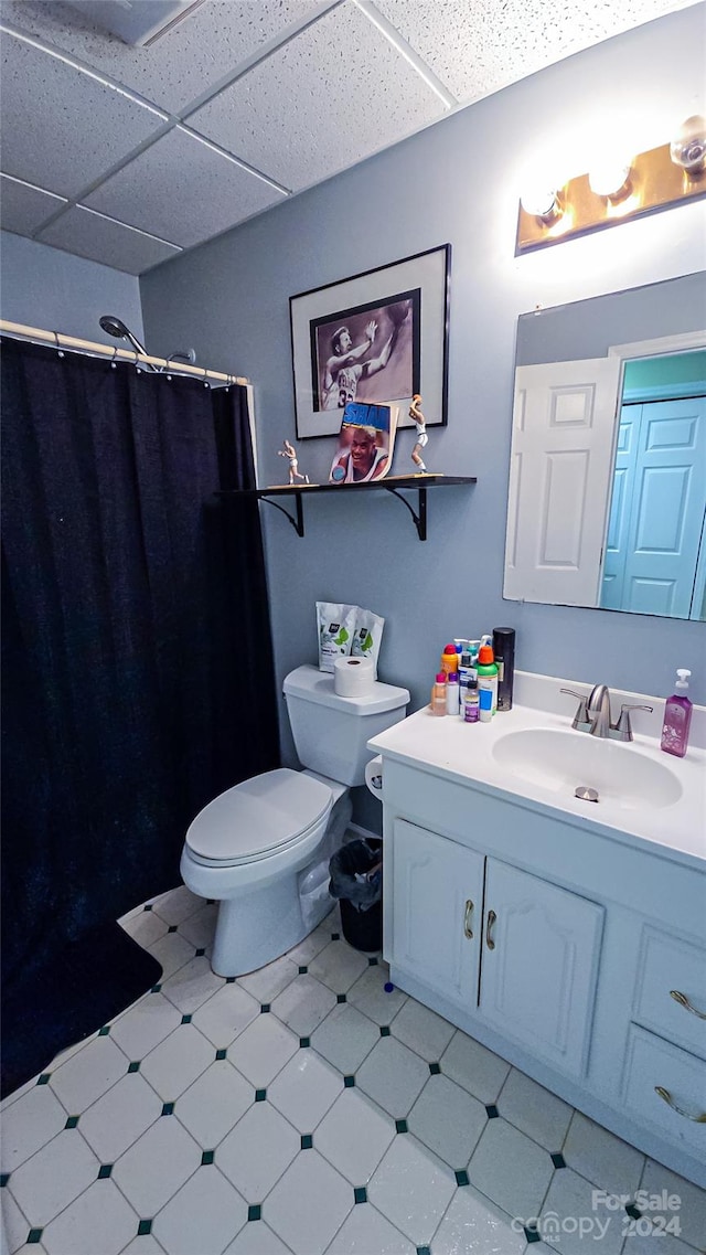 bathroom featuring vanity, toilet, walk in shower, and a drop ceiling