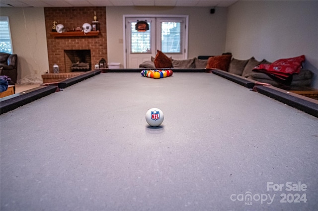 playroom with a paneled ceiling, billiards, and a brick fireplace