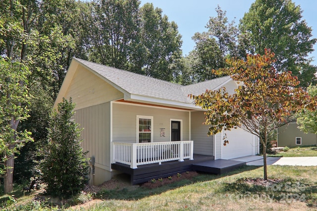 single story home with covered porch, a garage, and a front yard