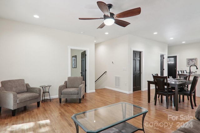 living room featuring sink, light hardwood / wood-style floors, and ceiling fan