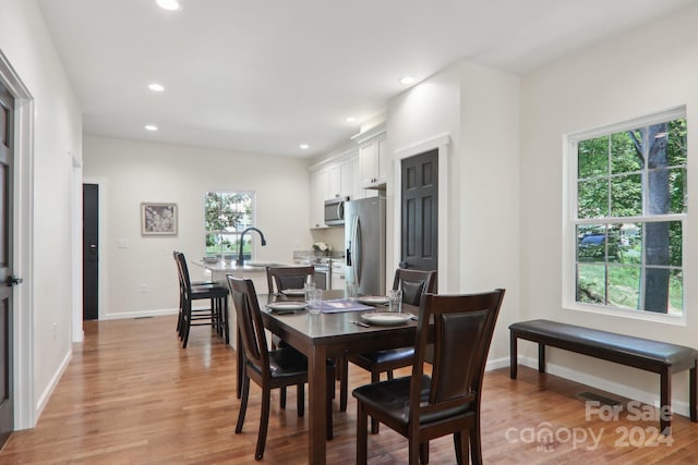 dining room with sink, a healthy amount of sunlight, and light hardwood / wood-style flooring