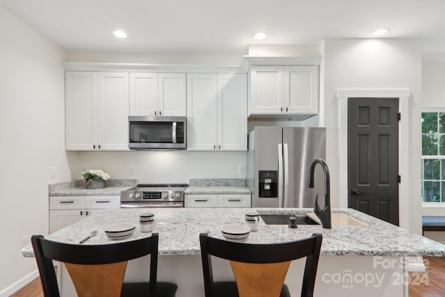 kitchen featuring appliances with stainless steel finishes, a center island with sink, and a breakfast bar area