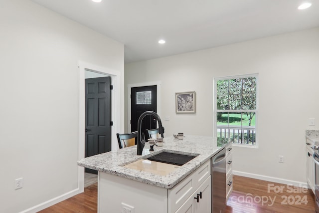 kitchen with a center island with sink, white cabinetry, stainless steel dishwasher, light hardwood / wood-style flooring, and sink