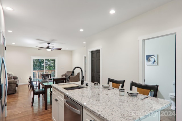 kitchen featuring a kitchen island with sink, stainless steel appliances, sink, a kitchen bar, and white cabinetry