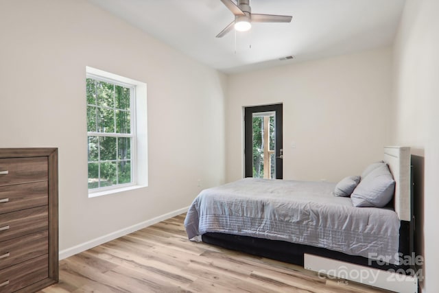 bedroom featuring ceiling fan, multiple windows, and light wood-type flooring