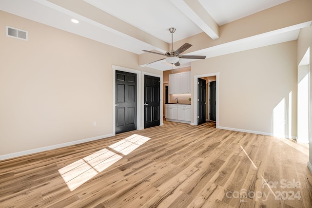 unfurnished bedroom with beam ceiling, light wood-type flooring, ensuite bath, and ceiling fan