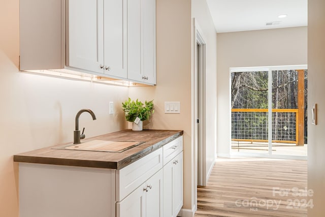 kitchen with white cabinets, light hardwood / wood-style flooring, and sink