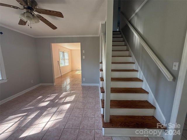 stairway with tile patterned floors, ornamental molding, and ceiling fan