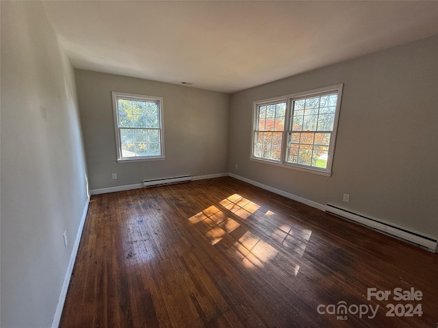 spare room with a baseboard heating unit and dark hardwood / wood-style flooring