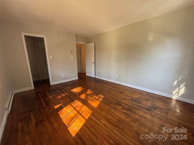 spare room featuring dark wood-type flooring and a baseboard heating unit