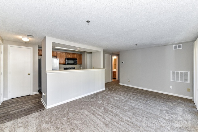 unfurnished living room featuring a textured ceiling and dark carpet