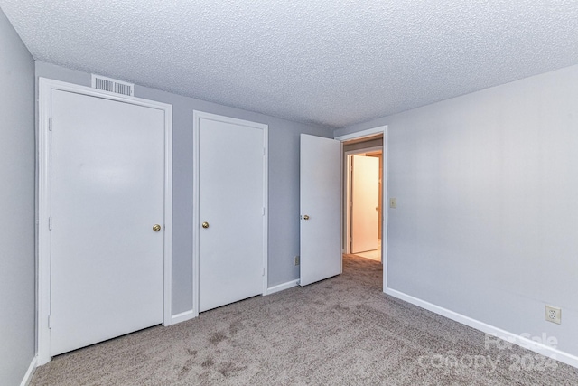 unfurnished bedroom featuring a textured ceiling and light colored carpet