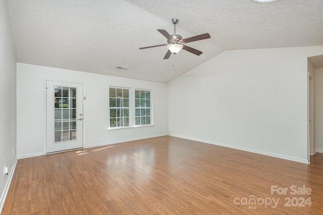 unfurnished room with hardwood / wood-style floors, vaulted ceiling, a textured ceiling, and ceiling fan