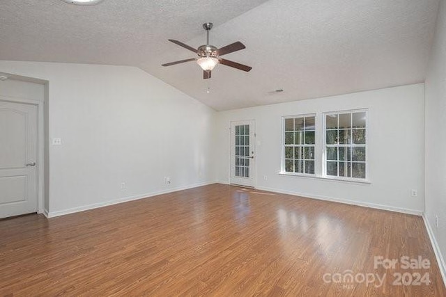 empty room featuring ceiling fan, a textured ceiling, wood-type flooring, and vaulted ceiling