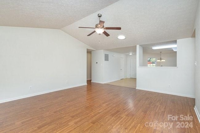 unfurnished living room with lofted ceiling, a textured ceiling, hardwood / wood-style flooring, and ceiling fan with notable chandelier