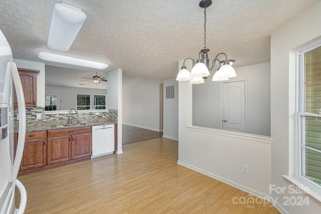 kitchen featuring tasteful backsplash, light wood-type flooring, pendant lighting, sink, and white appliances