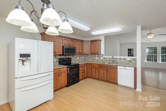 kitchen featuring white appliances, sink, a textured ceiling, pendant lighting, and light hardwood / wood-style flooring