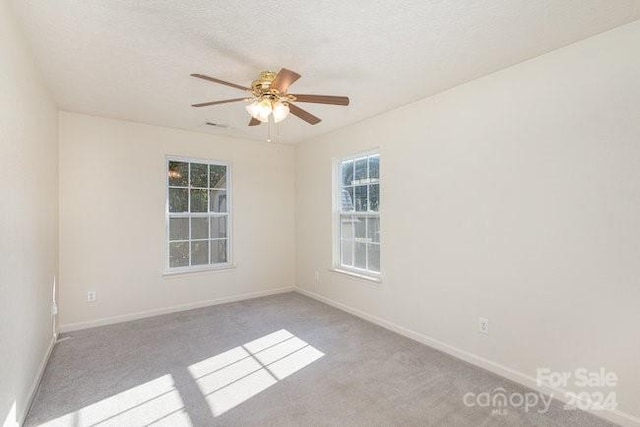 unfurnished room with a textured ceiling, light colored carpet, and ceiling fan